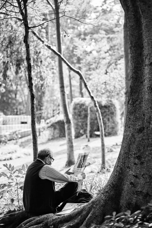 black and white pograph of a man sitting in a park