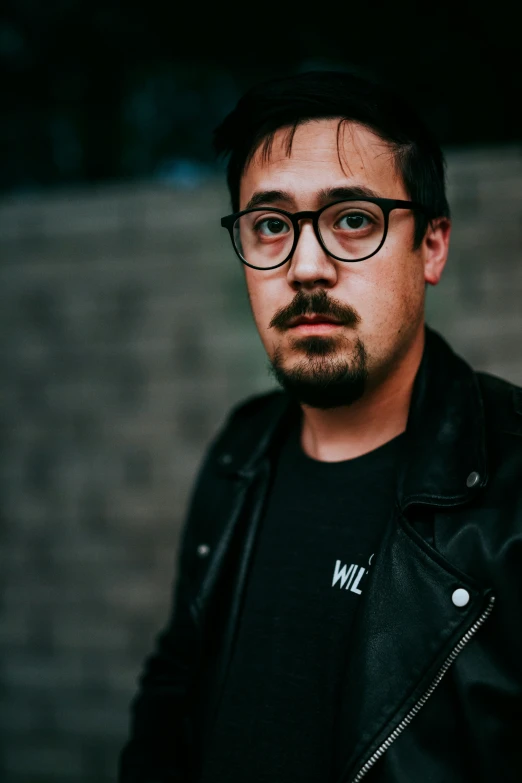 the man is posing for a pograph wearing glasses