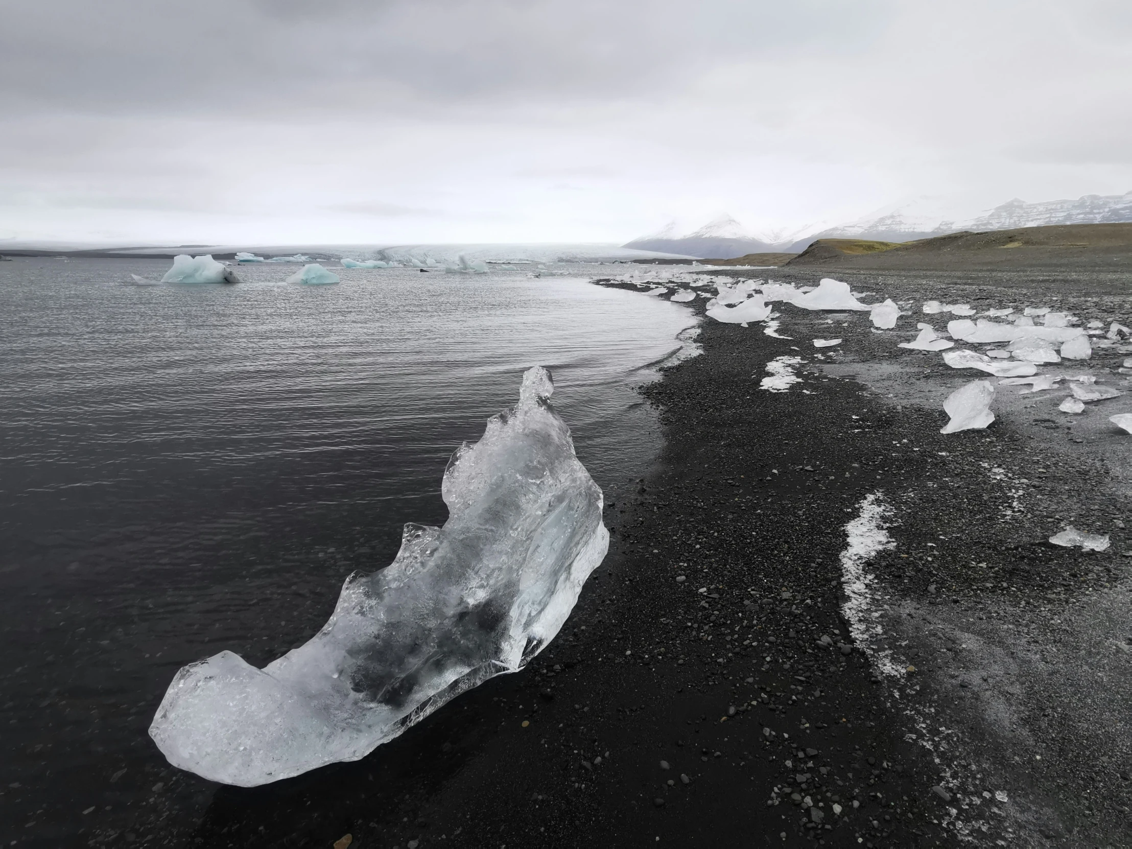 ice floating on the water in front of some mountains