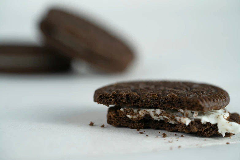 a sandwich with white filling next to two cookies