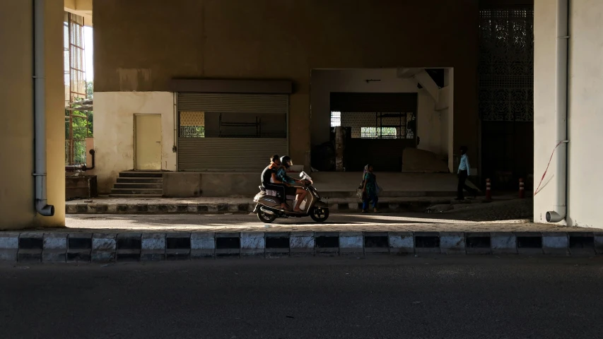 two people riding a moped on a street