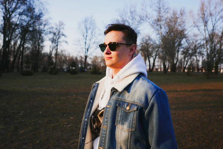 a young man wearing sunglasses and a jacket looking to his left