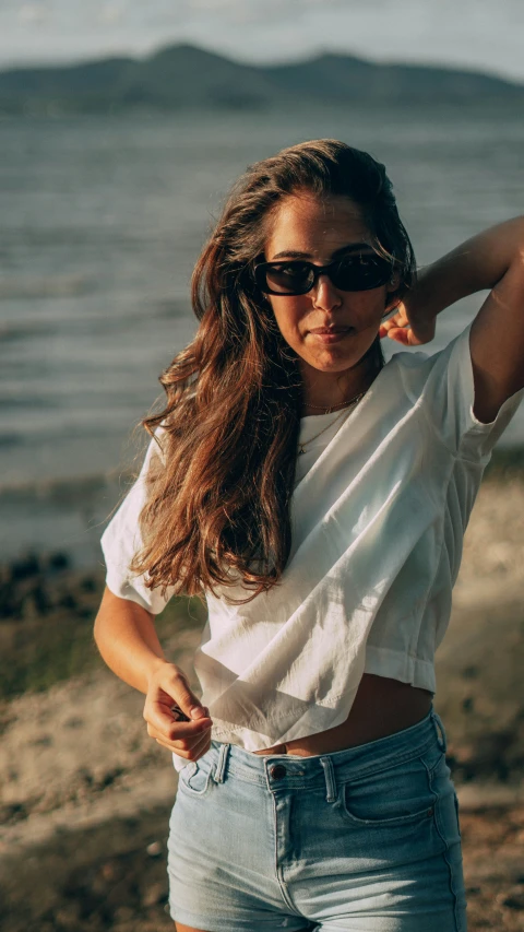 a woman with sunglasses standing in front of the ocean