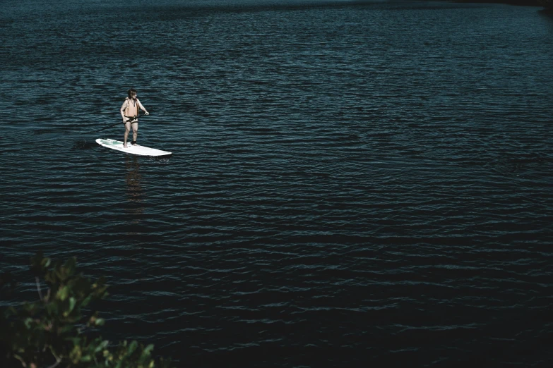 a man in a white suit rides a surfboard through water