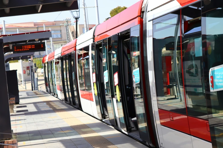 red and white public transit train stopped at a stop