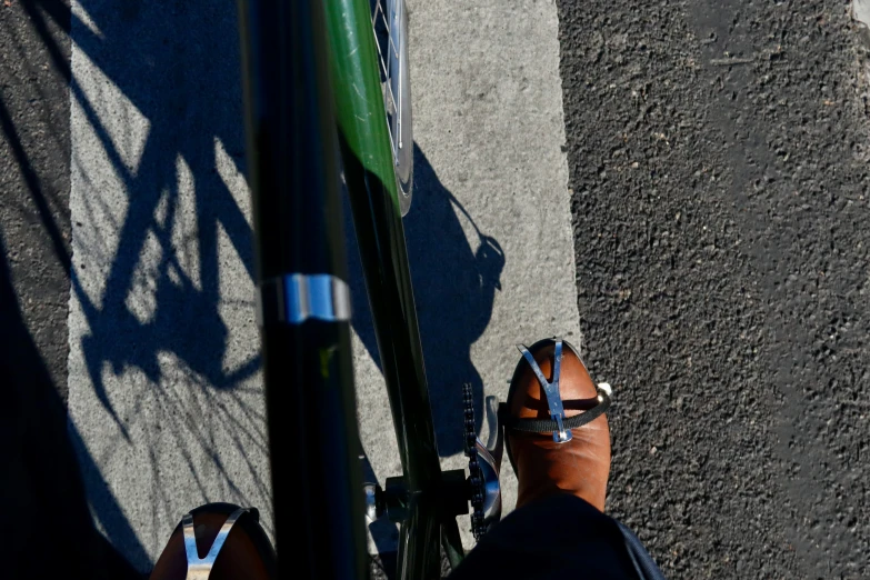 person standing next to bicycle in shadow on paved area