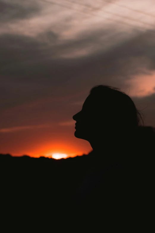 a woman is silhouetted in the setting sun