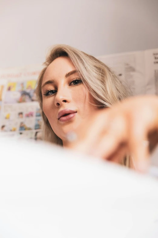 woman in bed looks at newspaper while looking at herself