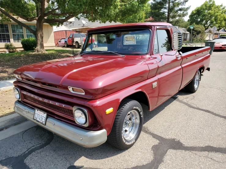 an old red pickup truck parked in the driveway