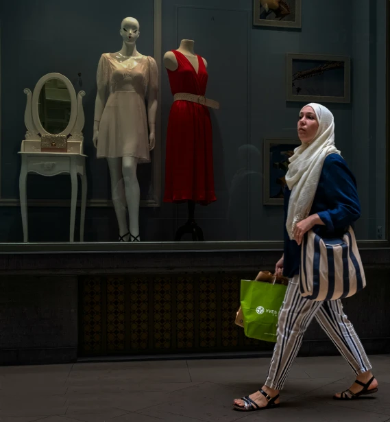 woman with scarf on walking past clothing mannequins