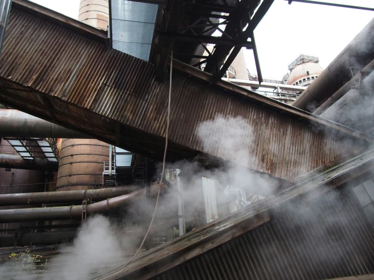 a train station with steam rising from it's pipe stacks