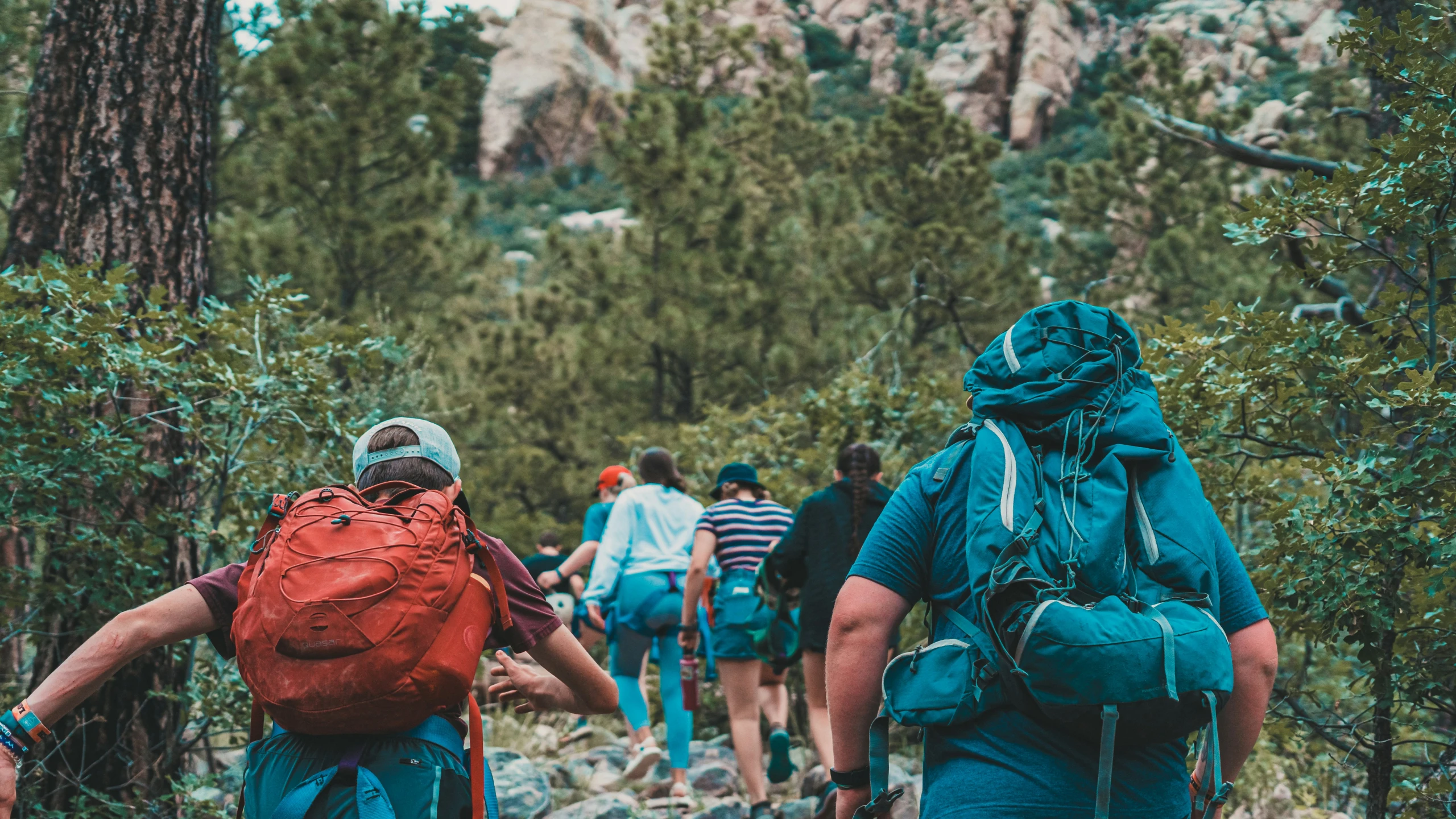 two men wearing backpacks walking up a trail