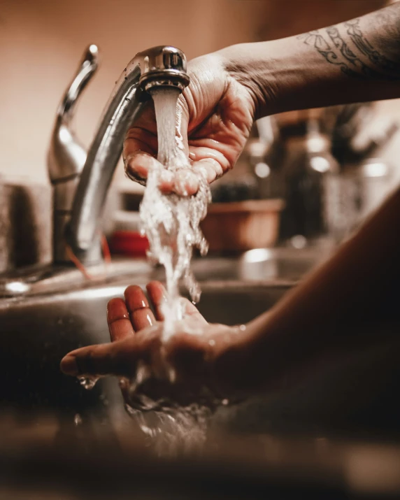 a woman's hand holding onto a faucet in a sink