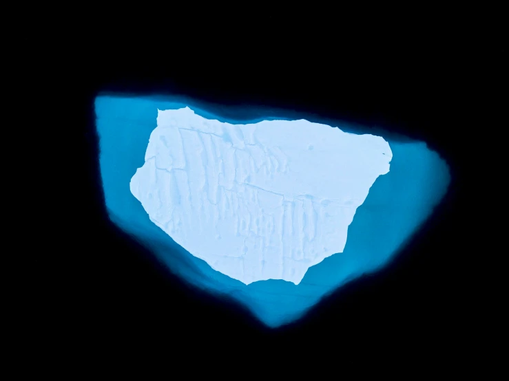 a very large iceberg in the dark with a little light