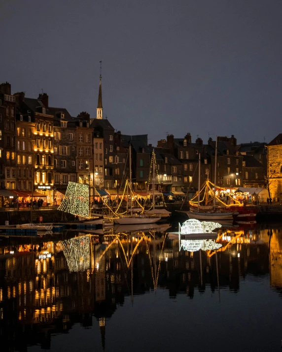 a christmas tree in the middle of a lake surrounded by buildings