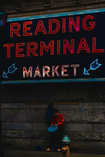 a red and blue lit sign that reads reading terminal market