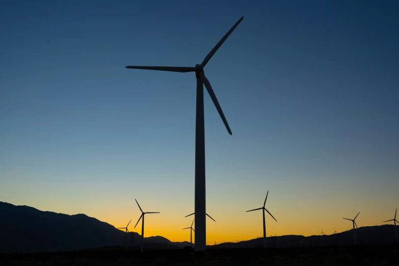 a wind turbine standing in front of the sun