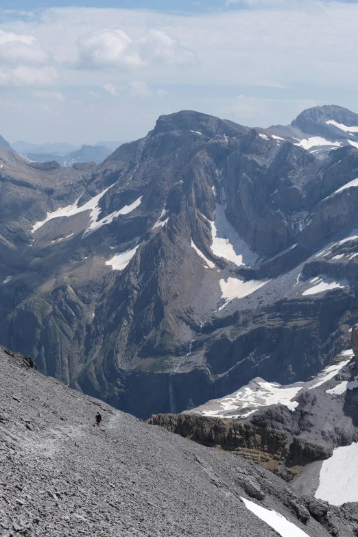 two people with backpacks walking along the side of a mountain