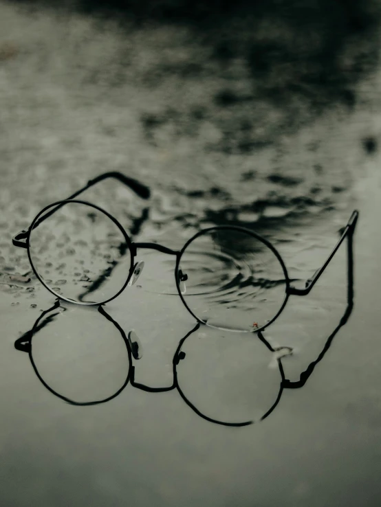 a pair of glasses sits on the ground covered in water