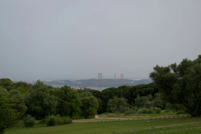 a picture of a field with an orange bridge in the background