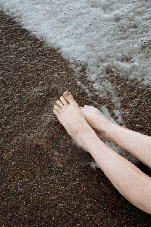 the person's feet on the beach are almost completely covered in water