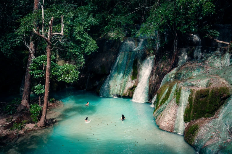 two people are skiing in a blue water pool surrounded by forest