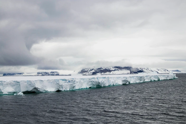 some icebergs floating in the ocean under gray skies