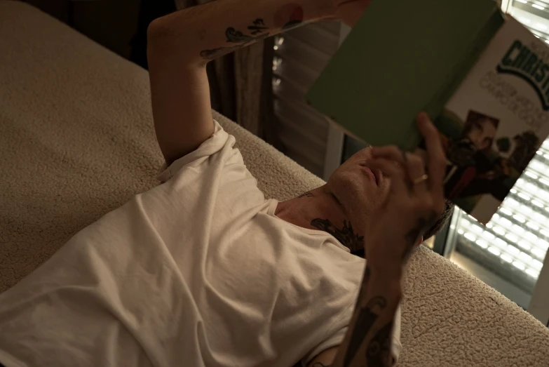 a man holding a book while laying on a couch