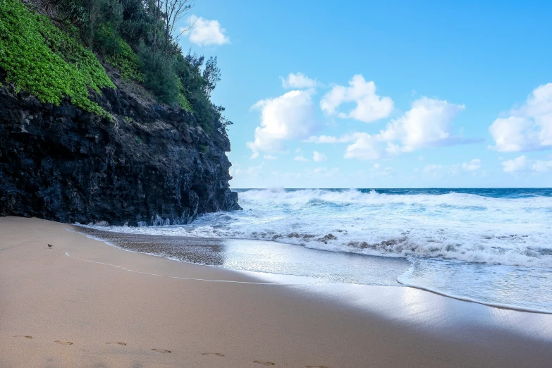 a sandy beach next to the ocean under a blue sky