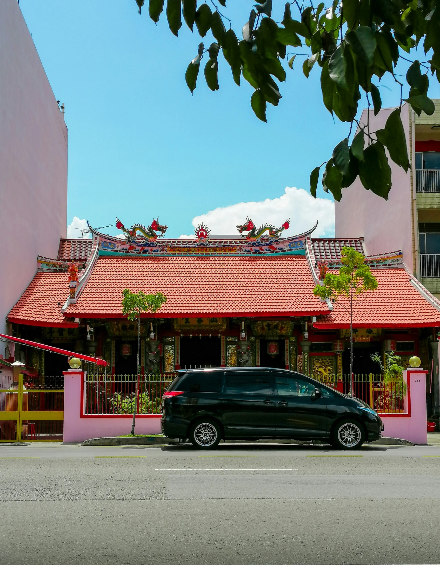 a black car parked next to a pink house