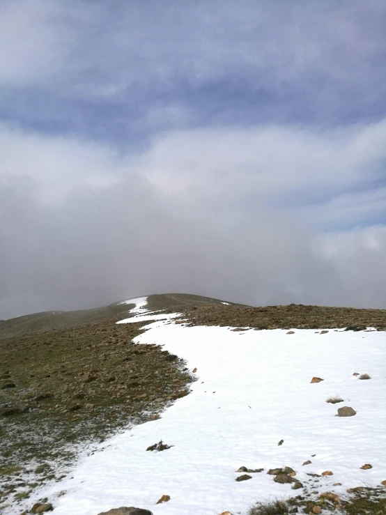 a snowy slope with rocks and a rock on it