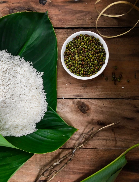 a bowl of white rice sitting next to a banana leaf