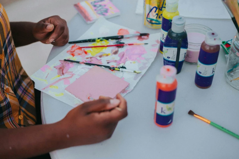 two people are holding paints and pens in front of paper