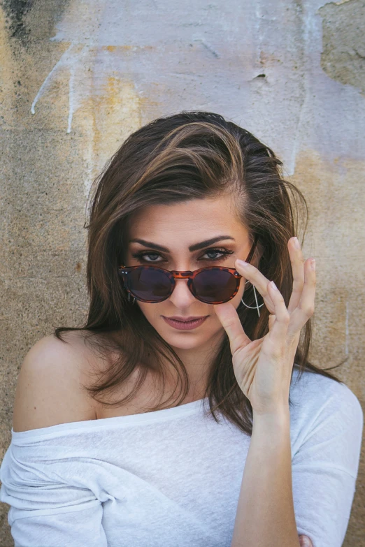 a woman in sunglasses holding her hand to her eye