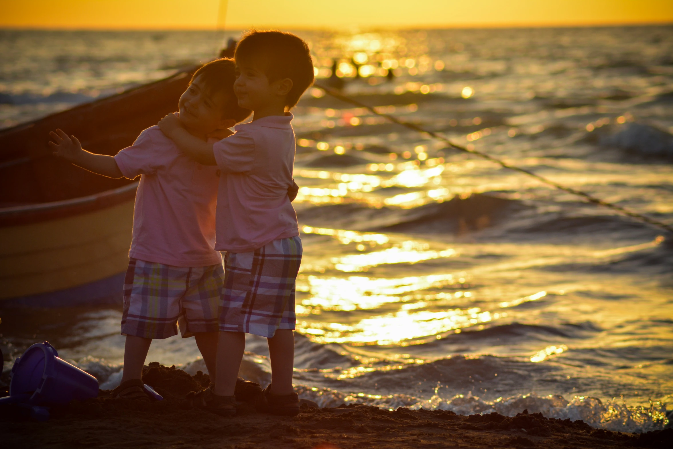 two young children by the shore as the sun sets