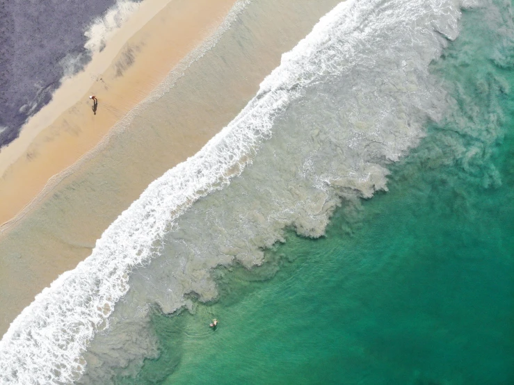 people walking along the shore line and riding surf boards