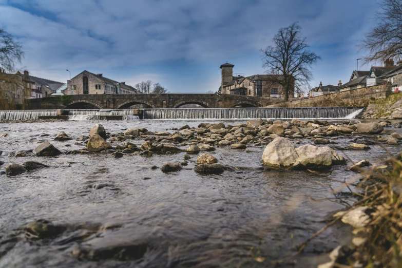 a river with rocks under a bridge and buildings