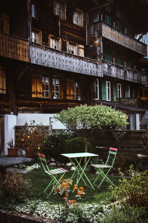 a patio with chairs and tables sits outside an apartment complex