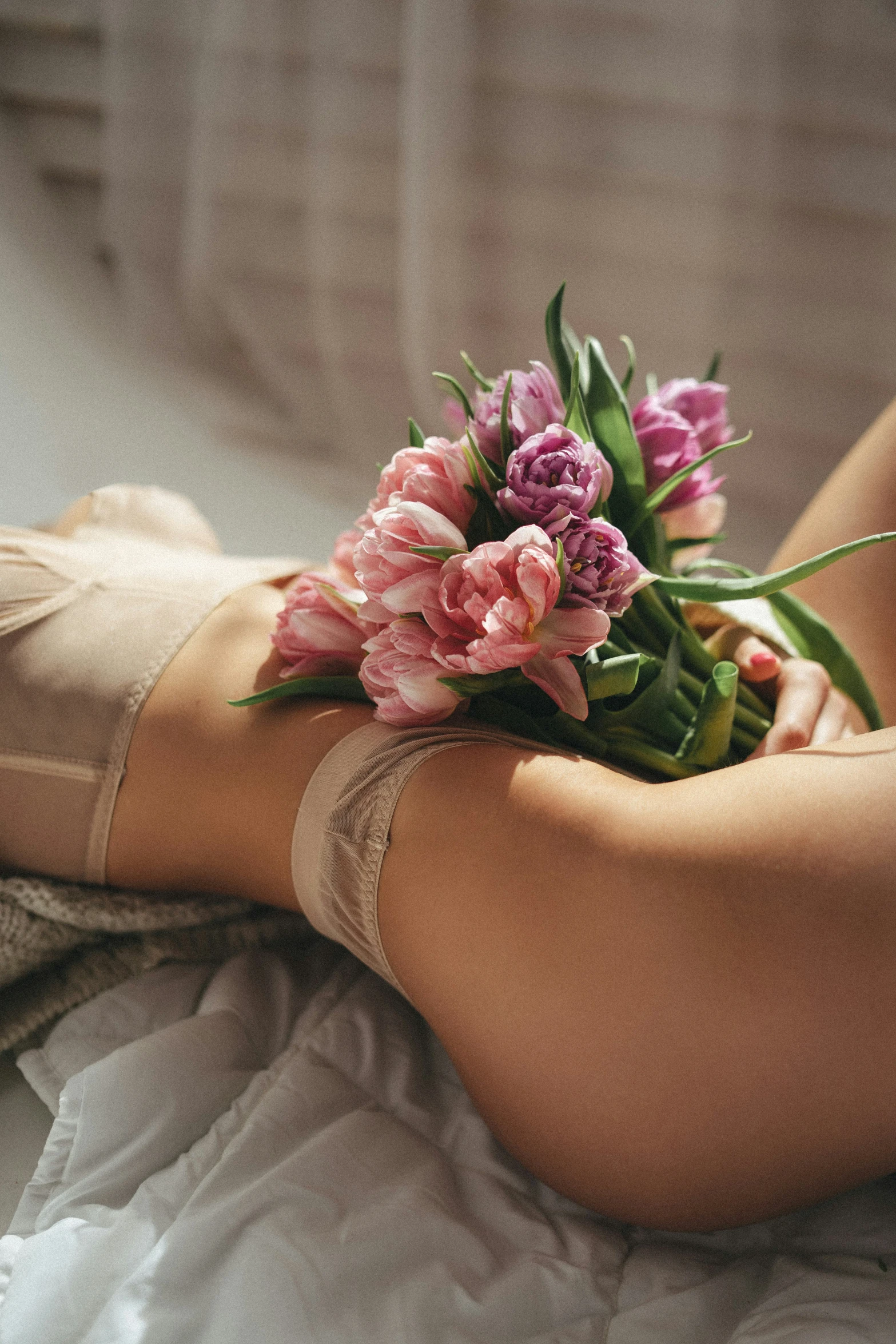 a close - up po shows the bottom half of a person's leg as she sits on a bed with flowers growing out of it