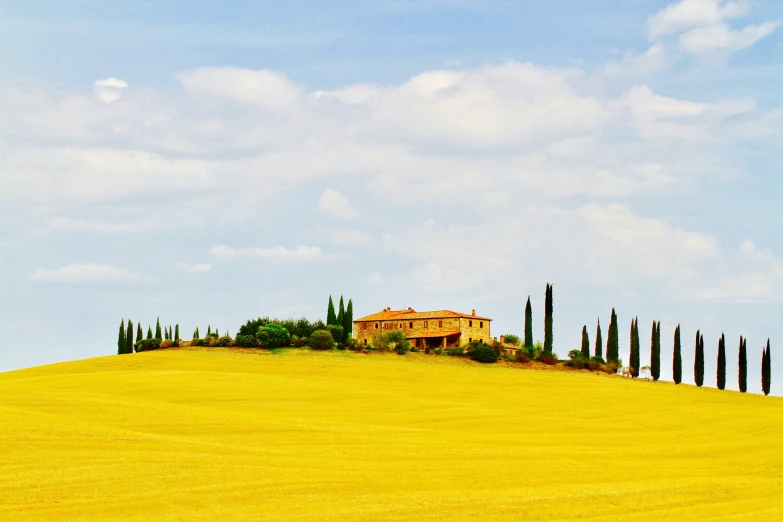 a lone yellow house is sitting on a hill