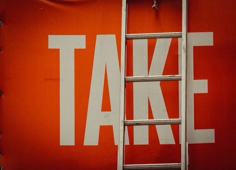 a large poster with a ladder leaning against it that reads take