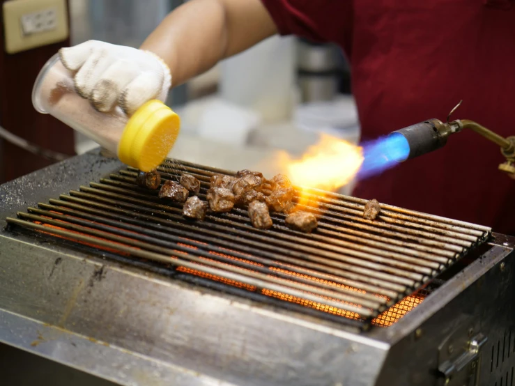 a person wearing gloves is grilling soing