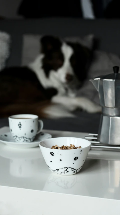 a dog laying on top of a white table next to some cups