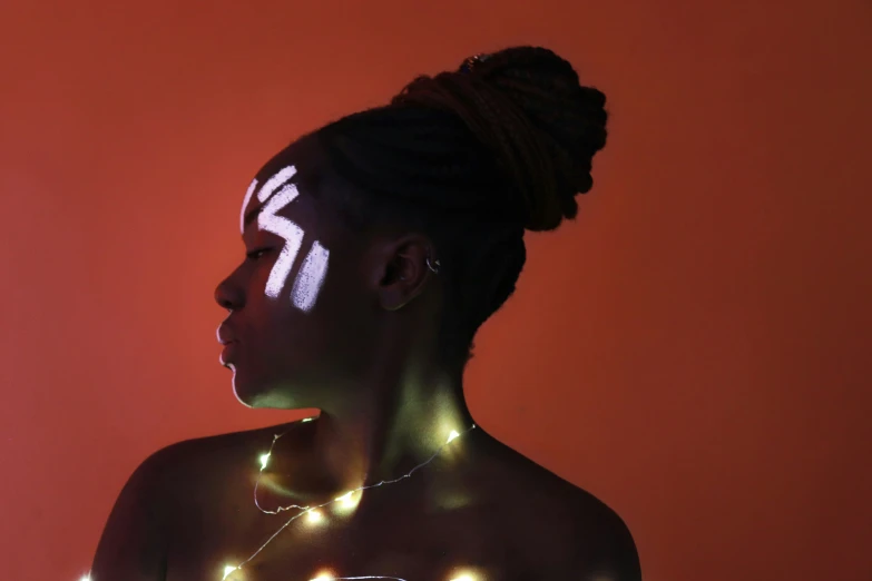 a young woman with face lights shining on her skin