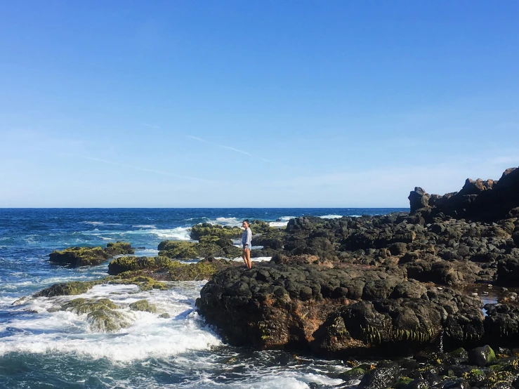 people standing on top of a rocky shore next to the ocean