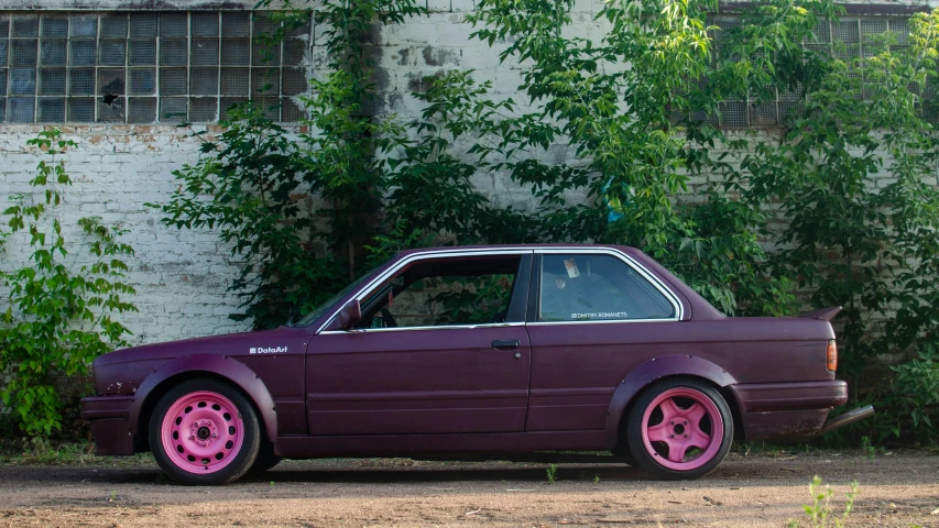 a purple car with pink wheels parked in front of a building