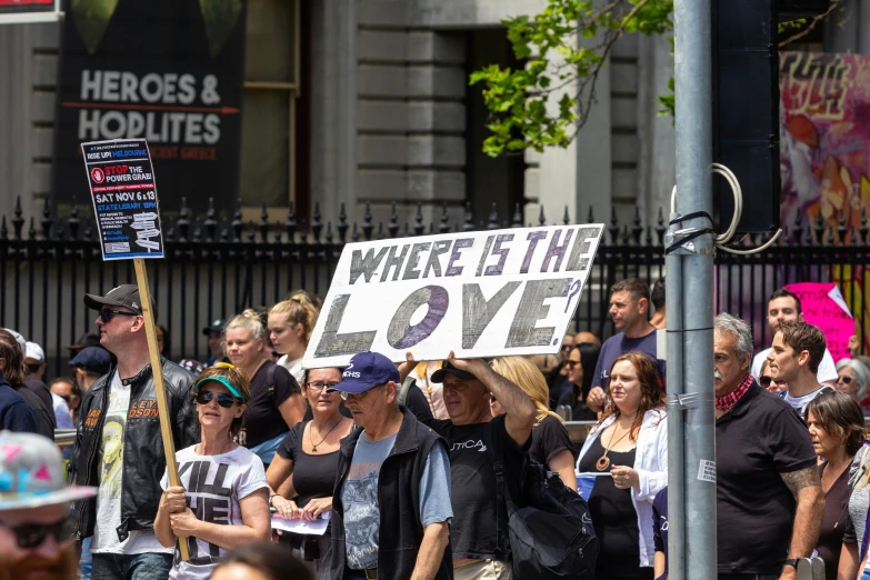 group of people holding a sign saying where is the love?