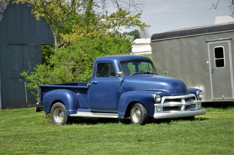 an old blue truck is parked on a grassy field