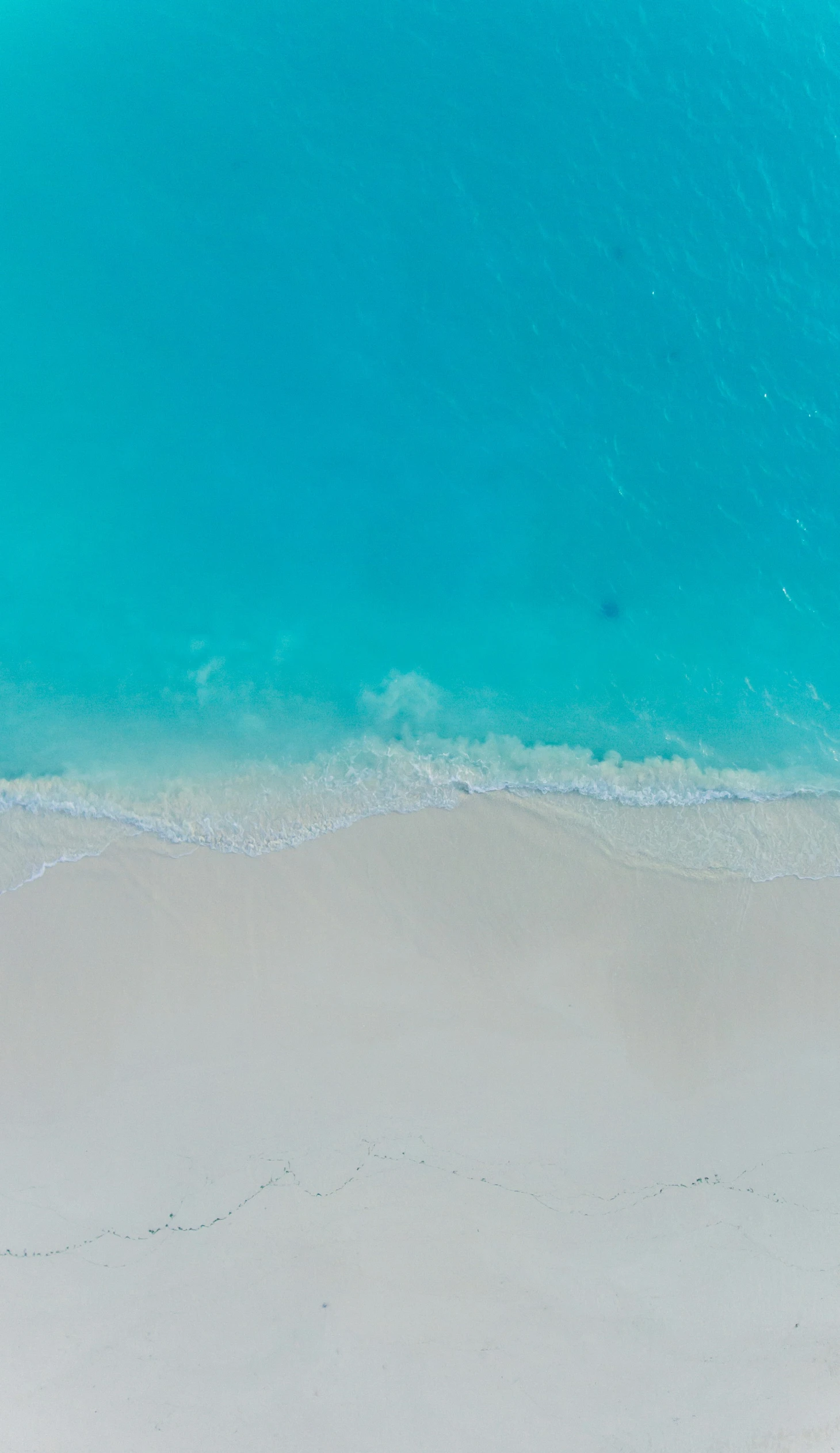 a person stands on the beach near the surf