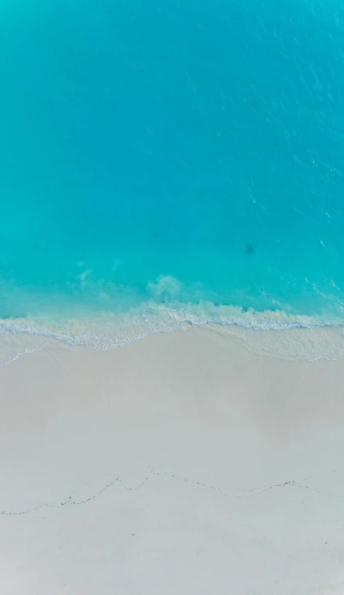 a person stands on the beach near the surf